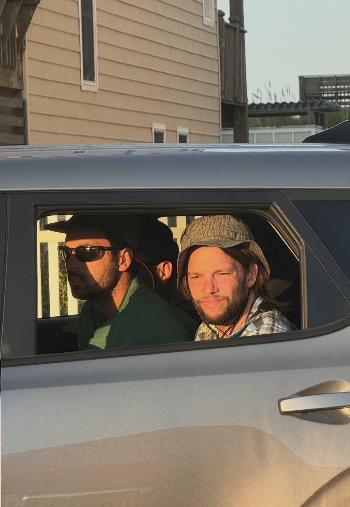 A man photographed through a car window, looking out with a weary expression.