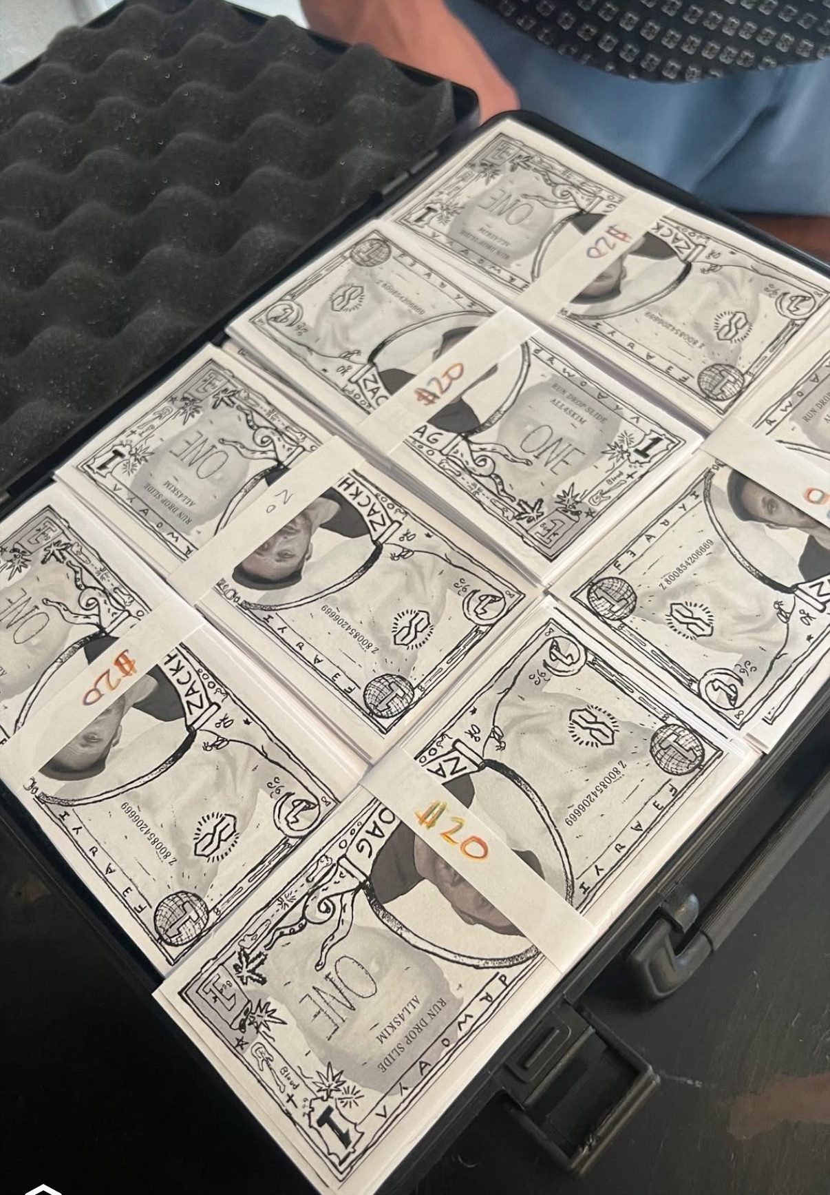 An open briefcase containing sheets of uncut notes and stacked verified bills.