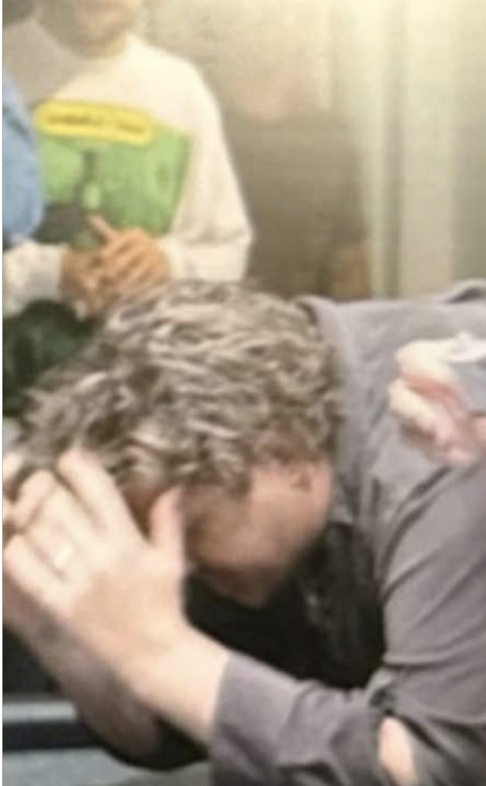 A man reacts with disbelief at a gaming table, hands raised, after a losing roll.