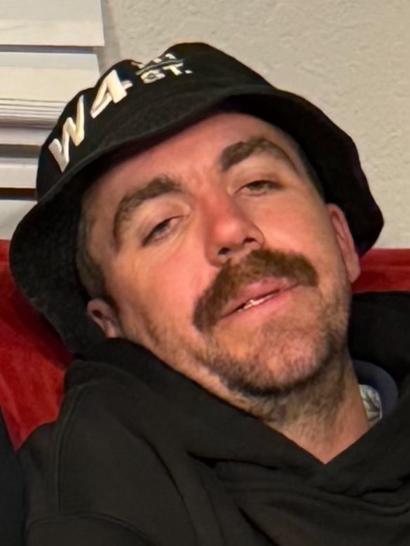 Portrait of a man in a cap looking directly at the camera with a composed expression.
